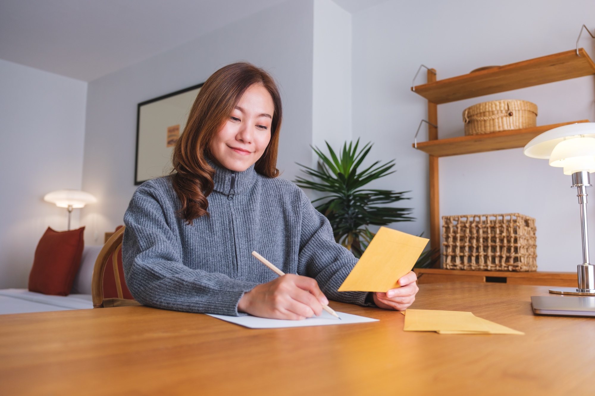 Portrait image of a young woman writing on a letter and envelopes
