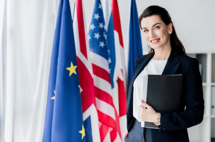 smiling ambassador looking at camera near flags