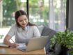 Asian woman is studying online and taking notes on the home.
