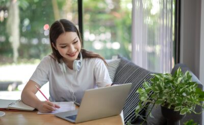 Asian woman is studying online and taking notes on the home.