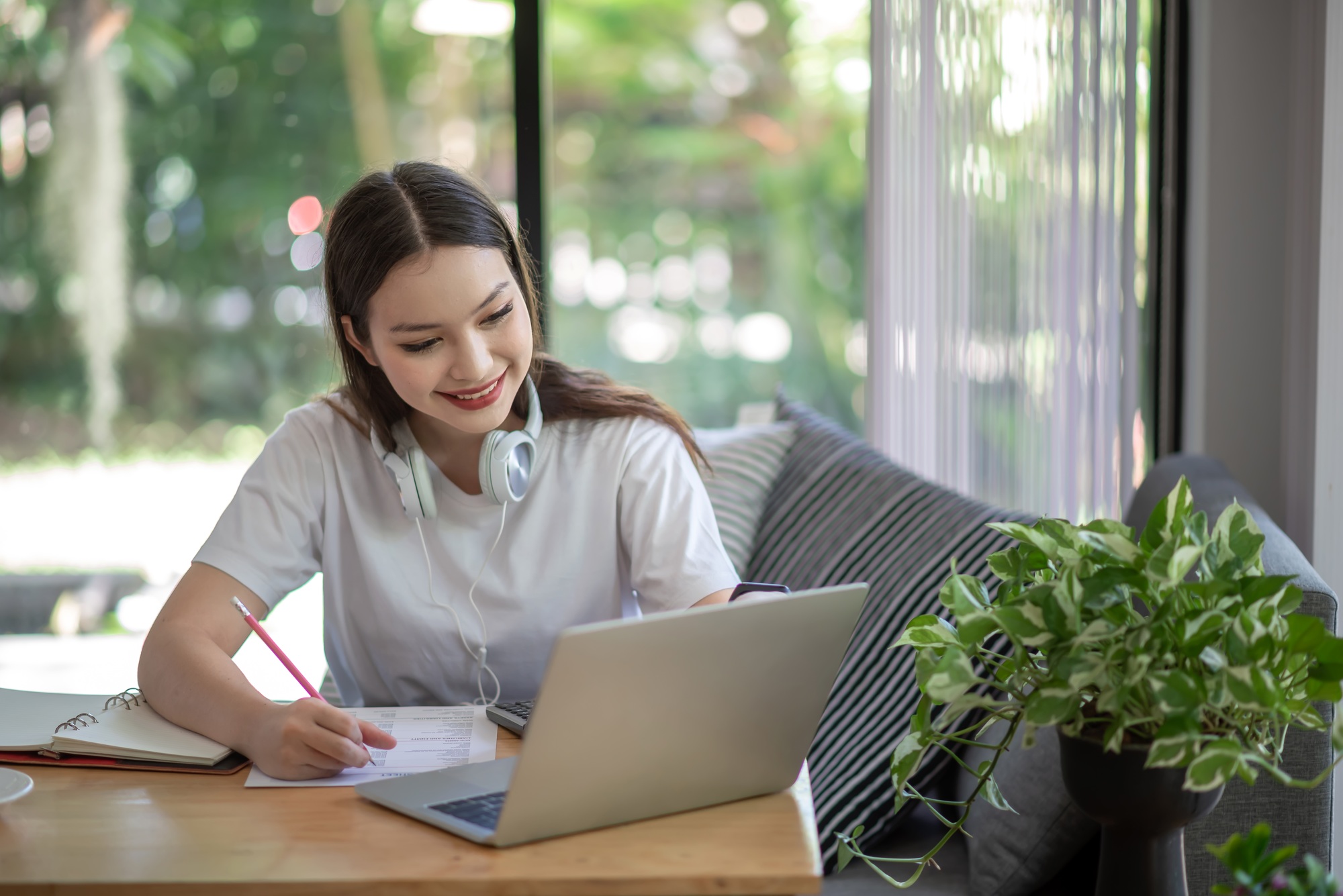Asian woman is studying online and taking notes on the home.