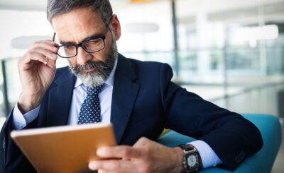 Business, technology and people concept - senior businessman with tablet pc working in office