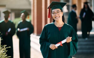 Happy Asian female student with bachelor's degree on her graduation day looking at camera.