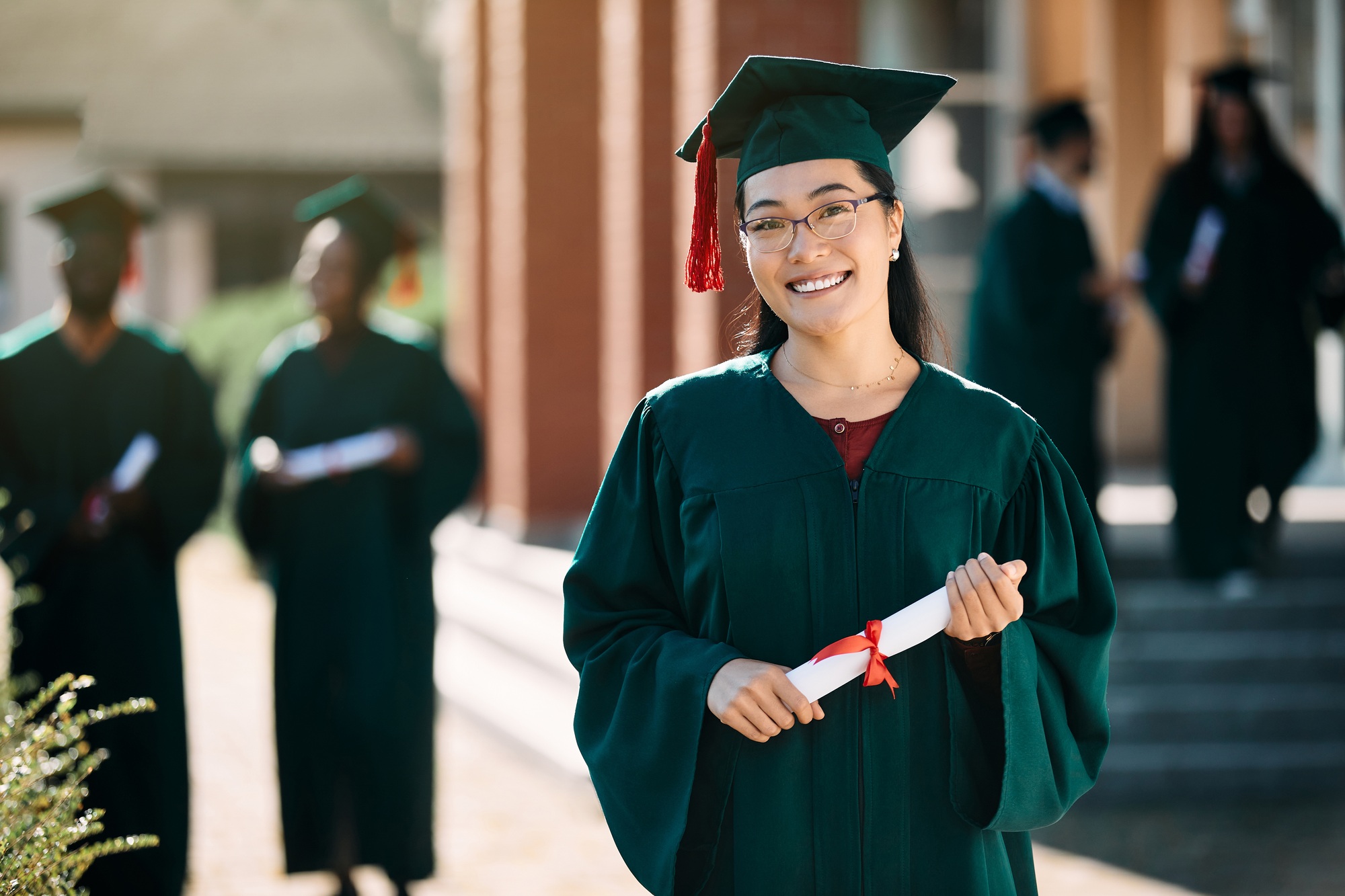 Happy Asian female student with bachelor's degree on her graduation day looking at camera.